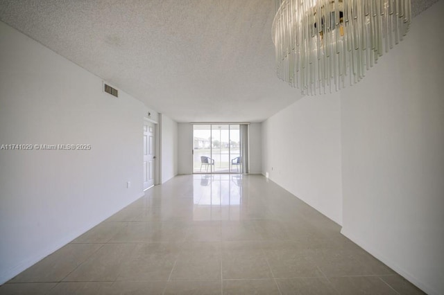tiled empty room with floor to ceiling windows and a textured ceiling