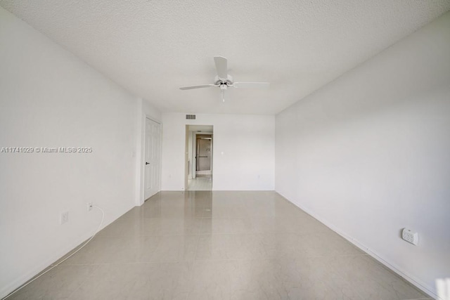 empty room with ceiling fan and a textured ceiling