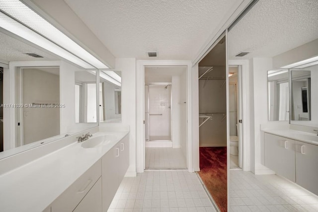 bathroom with tile patterned flooring, toilet, a textured ceiling, and walk in shower