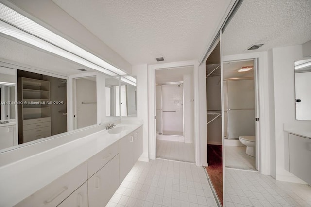 bathroom featuring vanity, an enclosed shower, a textured ceiling, tile patterned floors, and toilet