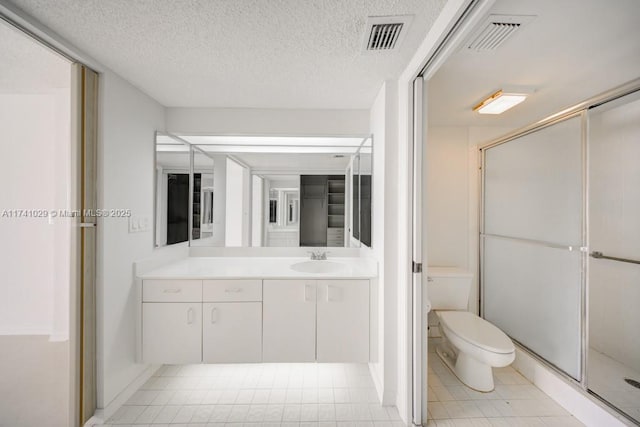 bathroom featuring vanity, an enclosed shower, a textured ceiling, and toilet
