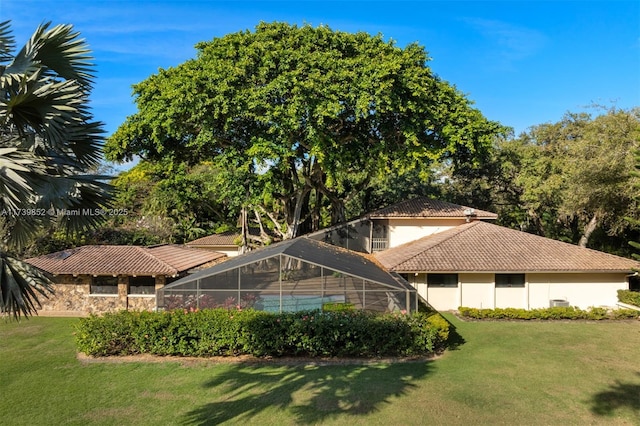 rear view of house with glass enclosure and a lawn