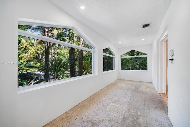 unfurnished sunroom featuring lofted ceiling and visible vents