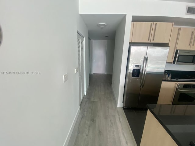 kitchen with appliances with stainless steel finishes, light brown cabinetry, and light hardwood / wood-style flooring