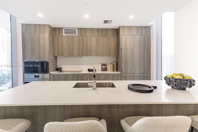 kitchen with sink, black appliances, and a kitchen bar