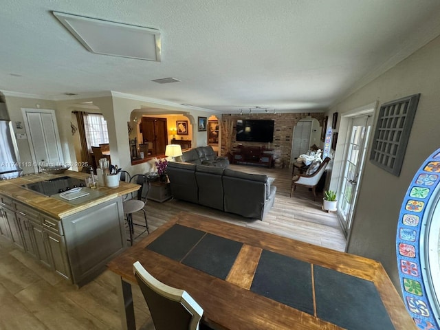 interior space with ornamental molding, a textured ceiling, and light wood-type flooring