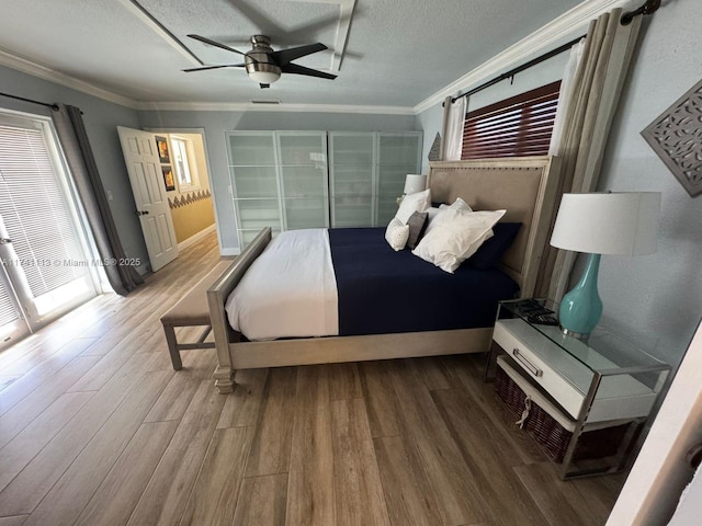 bedroom featuring multiple windows, hardwood / wood-style floors, crown molding, and a textured ceiling