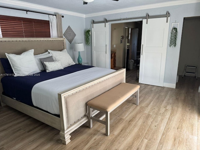 bedroom with crown molding, a barn door, and hardwood / wood-style floors