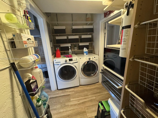 laundry room with washing machine and clothes dryer and hardwood / wood-style floors