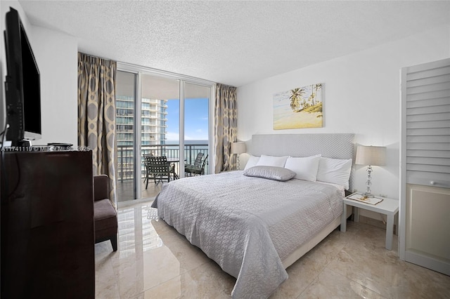 bedroom featuring expansive windows, a water view, access to outside, and a textured ceiling