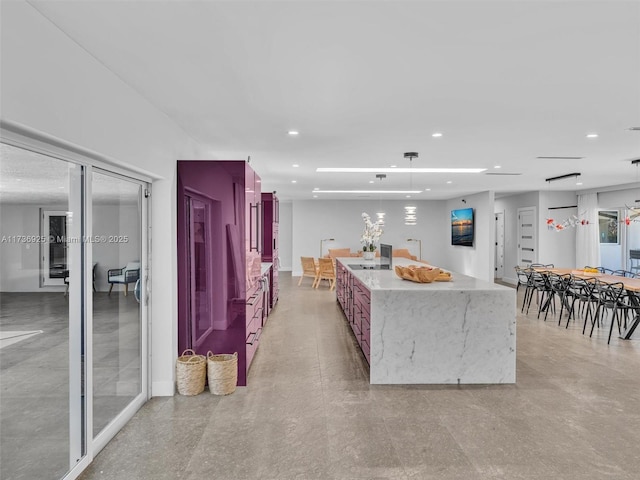 kitchen featuring pendant lighting, light stone countertops, and a kitchen island