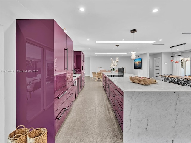 kitchen featuring pendant lighting, light stone countertops, and a spacious island