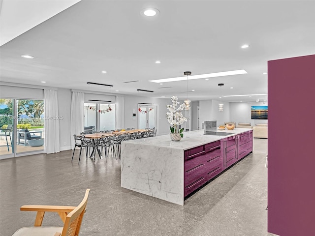 kitchen with light stone counters, black electric stovetop, a large island, and decorative light fixtures