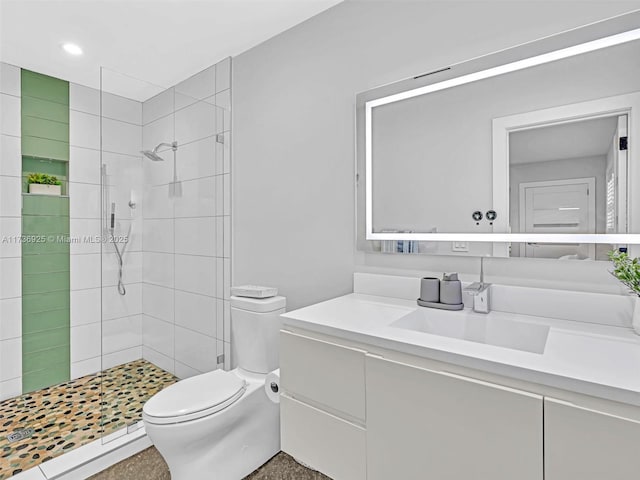 bathroom with vanity, a tile shower, and toilet