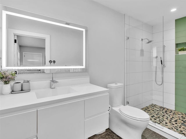 bathroom featuring vanity, a tile shower, and toilet