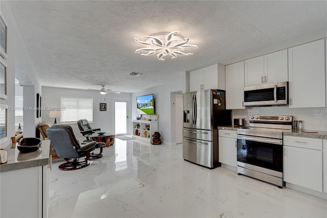 kitchen featuring white cabinetry, stainless steel appliances, a textured ceiling, and open floor plan