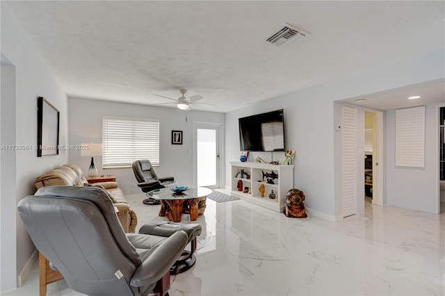 living area with a textured ceiling, marble finish floor, visible vents, and baseboards