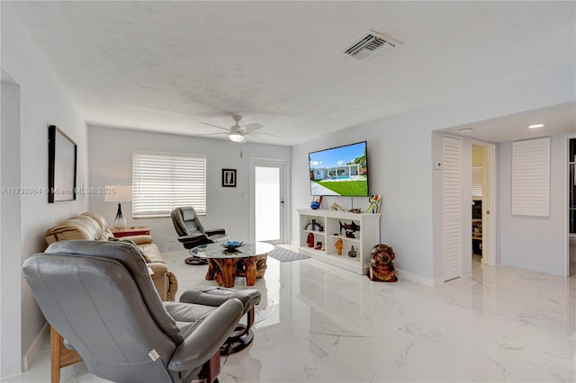 living area with a textured ceiling, ceiling fan, visible vents, baseboards, and marble finish floor