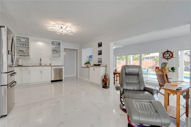 kitchen with stainless steel appliances, glass insert cabinets, open floor plan, white cabinetry, and a sink