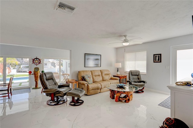 living area featuring a textured ceiling, ceiling fan, visible vents, baseboards, and marble finish floor