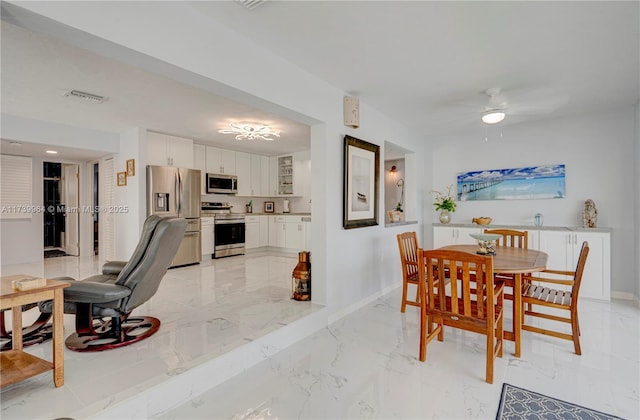 dining space featuring marble finish floor, visible vents, baseboards, and a ceiling fan