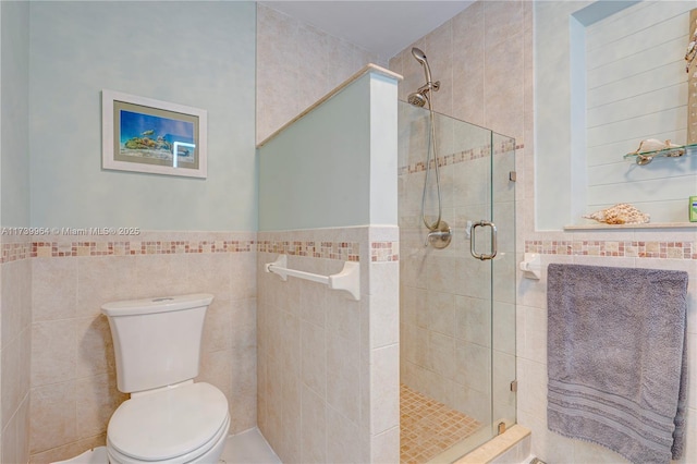 full bathroom with toilet, a wainscoted wall, a shower stall, and tile walls