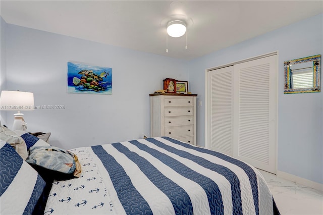 bedroom featuring marble finish floor, a ceiling fan, baseboards, and a closet