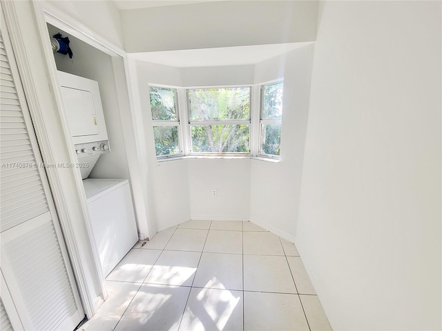 laundry area with light tile patterned floors and stacked washer and clothes dryer