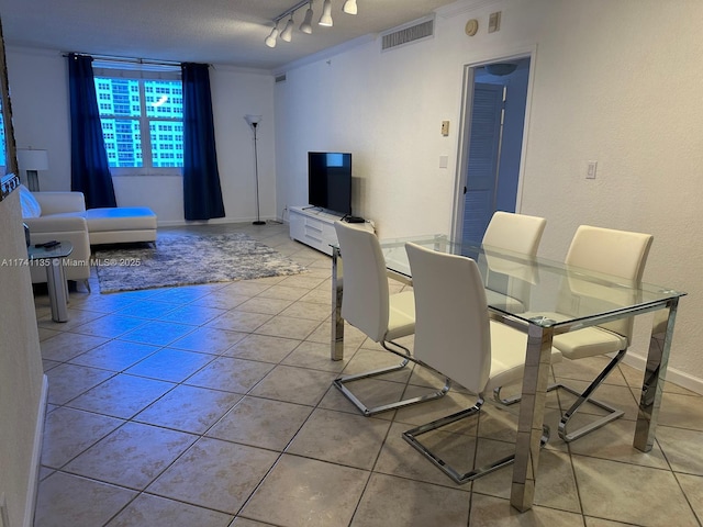 tiled dining area featuring crown molding and rail lighting