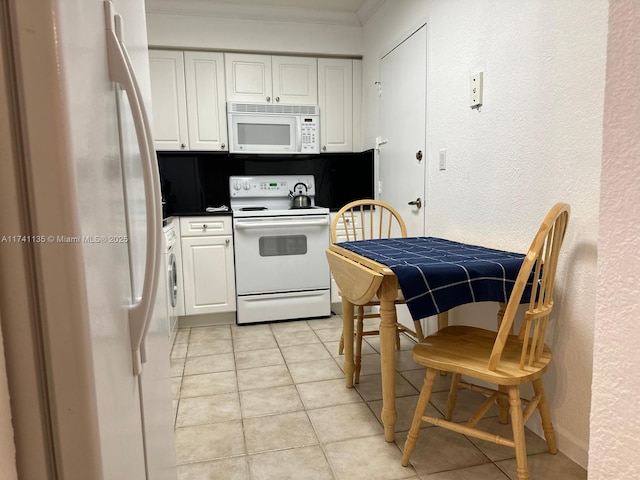 kitchen with white cabinetry, crown molding, light tile patterned flooring, and white appliances