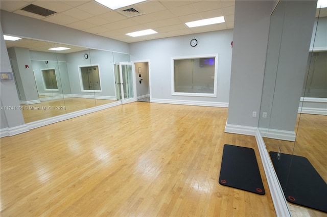 exercise area featuring light hardwood / wood-style flooring and a drop ceiling