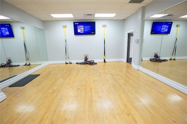 exercise room featuring hardwood / wood-style flooring and a drop ceiling