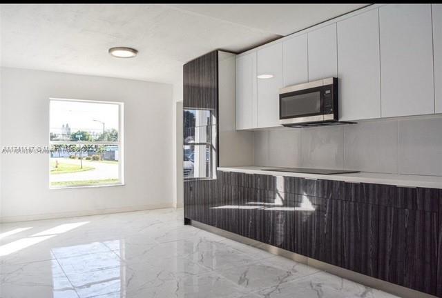 kitchen with black electric stovetop and white cabinets