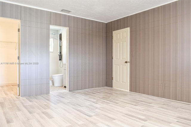 unfurnished room featuring light hardwood / wood-style flooring and a textured ceiling