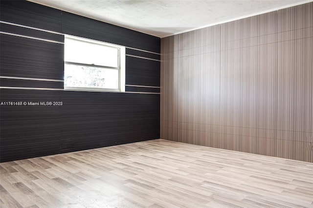 spare room with light hardwood / wood-style flooring and a textured ceiling