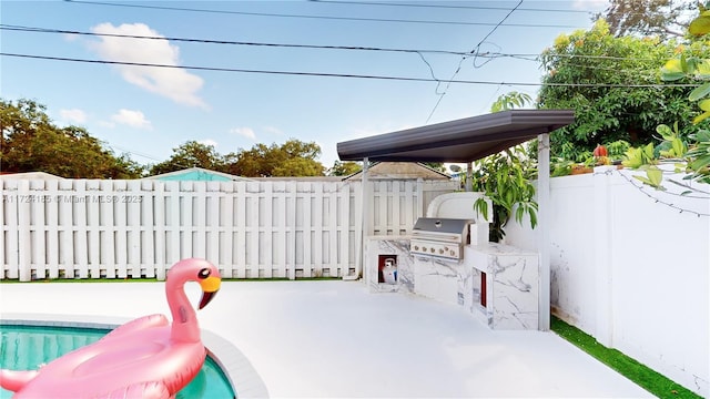 view of patio / terrace featuring a fenced in pool, grilling area, and exterior kitchen