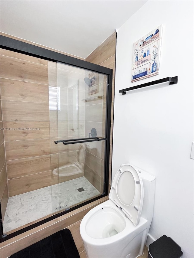 bathroom featuring a shower with shower door and toilet