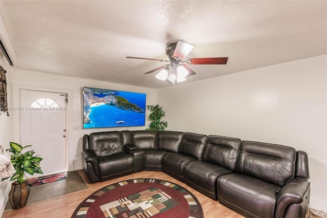 living room with hardwood / wood-style floors, a textured ceiling, and ceiling fan