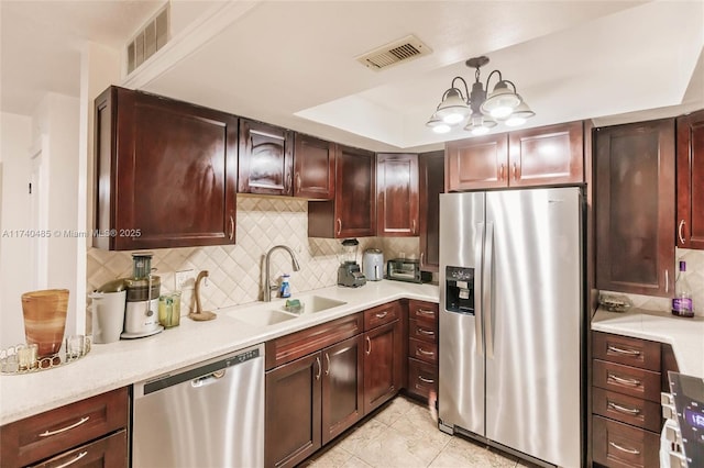 kitchen with sink, tasteful backsplash, decorative light fixtures, a tray ceiling, and stainless steel appliances