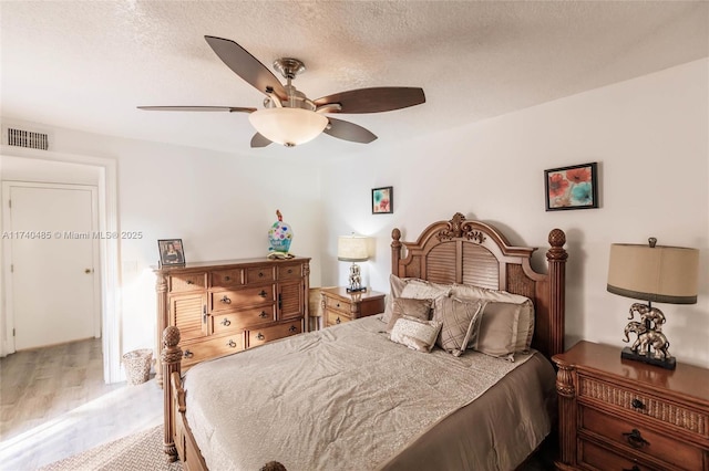 bedroom with ceiling fan, light hardwood / wood-style flooring, and a textured ceiling