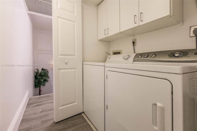 laundry area featuring cabinets, washer and clothes dryer, and light wood-type flooring