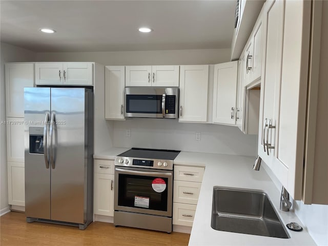 kitchen featuring stainless steel appliances, white cabinets, and light wood-type flooring