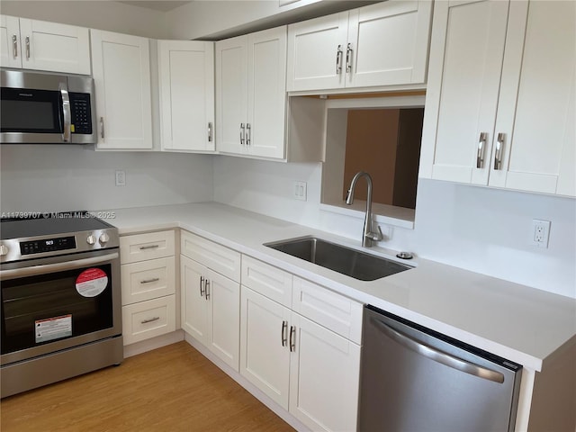 kitchen with white cabinetry, stainless steel appliances, light hardwood / wood-style floors, and sink