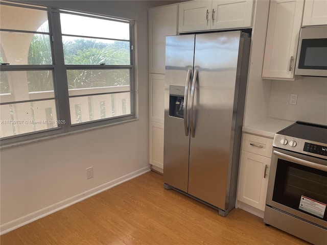 kitchen featuring stainless steel appliances, light wood-type flooring, and white cabinets