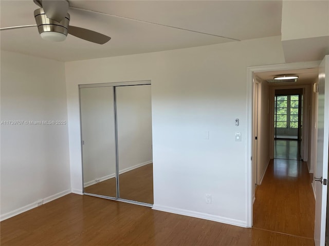 unfurnished bedroom featuring dark wood-type flooring, ceiling fan, and a closet