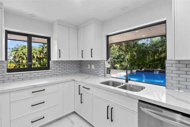 11965 SW 15th Ct, Davie, FL 33325 - kitchen featuring stainless steel dishwasher, a sink, decorative backsplash, light marble finish flooring, and white cabinets