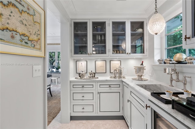 bar with sink, light stone countertops, ornamental molding, and decorative light fixtures