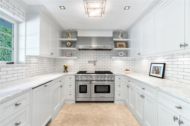 kitchen with white cabinets, island exhaust hood, light stone countertops, and range with two ovens