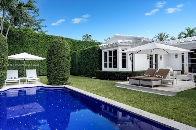 rear view of property featuring a lawn, french doors, a patio, an outdoor structure, and a fenced in pool