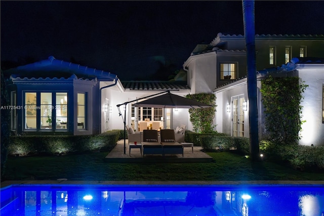 back house at night featuring french doors, outdoor lounge area, and a patio area